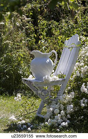 Stock Photography - White jug on white table in country garden in summer. Fotosearch