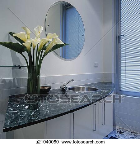 White lilies in vase on marble-topped fitted vanity unit below modern circular mirror View Large Photo Image Stock Image - White lilies in vase on marble-topped fitted vanity unit below modern circular mirror. Fotosearch