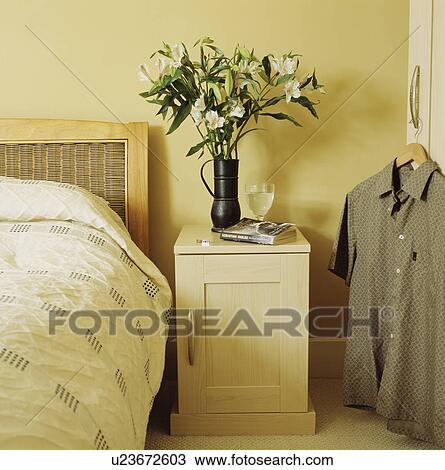 White lilies on cream wood bedside cabinet in neutral bedroom with beige shirt on cupboard door View Large Photo Image Stock Image - White lilies on cream wood bedside cabinet in neutral bedroom with beige shirt on cupboard door. Fotosearch