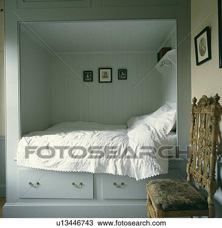 White linen on built-in bed above storage drawers in small grey guest room with antique chair View Large Photo Image Stock Image - White linen on built-in bed above storage drawers in small grey guest room with antique chair. Fotosearch