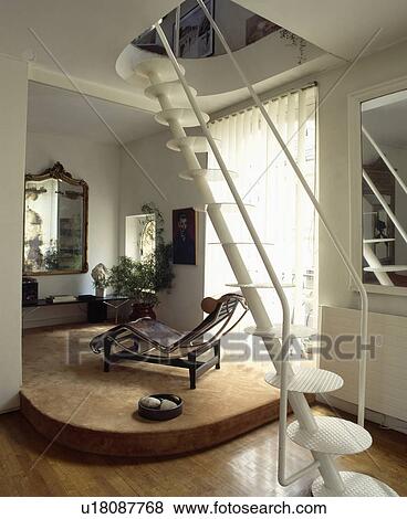 Stock Photo - White metal staircase with flat circular treads in eighties modern hall with Le Corbusier chaiselongue. Fotosearch