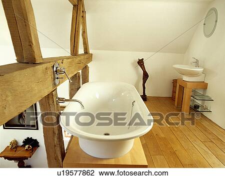 White Rolltop Bath On Platform Beside Large Open Beams In Modern