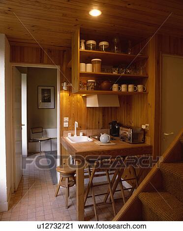 White sink in table and wooden wall shelves in compact wooden kitchen beside staircase View Large Photo Image Stock Image - White sink in table and wooden wall shelves in compact wooden kitchen beside staircase. Fotosearch
