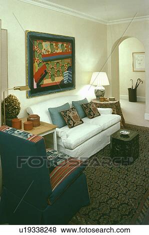 Stock Photo - White sofa below modern painting in traditional living room. Fotosearch