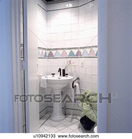 Stock Image - White tiled Water Closet with traditional style basin . Fotosearch