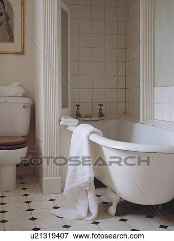 White towel on the side of clawfoot bath in traditional bathroom with ceramic tiled floor View Large Photo Image Stock Photo - White towel on the side of clawfoot bath in traditional bathroom with ceramic tiled floor. Fotosearch