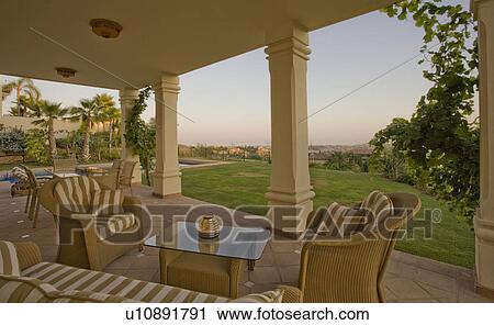 Wicker armchairs and sofa with cream and brown striped cushions on veranda with view of lawn View Large Photo Image Stock Image - Wicker armchairs and sofa with cream and brown striped cushions on veranda with view of lawn. Fotosearch
