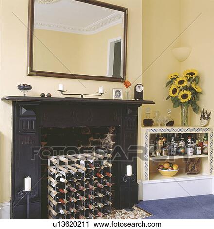 Download Wine Storage In Fireplace Below Large Mirror In Pastel Yellow Dining Room With Sunflowers And Liqueur Bottles On Shelving Stock Image U13620211 Fotosearch Yellowimages Mockups