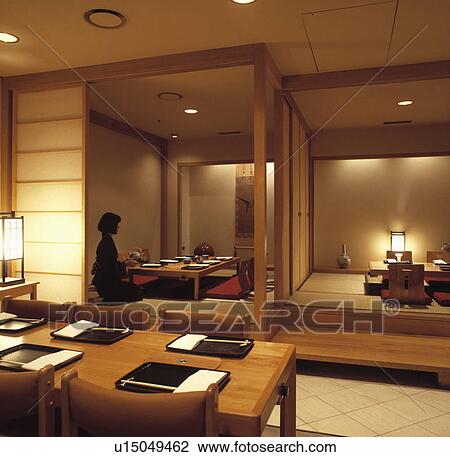 Stock Image - Woman sitting at table in Japanese restaurant. Fotosearch