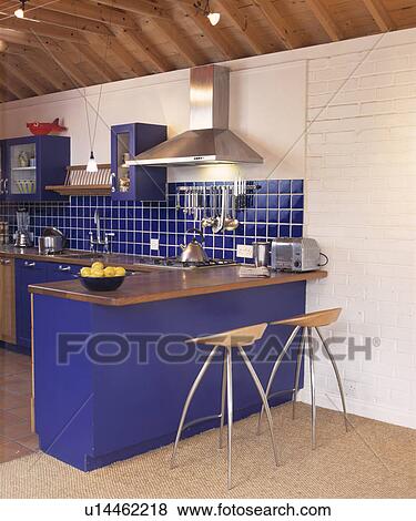 Wood and chrome stools at breakfast bar on bright blue counter in modern kitchen with blue wall tiles View Large Photo Image Stock Photo - Wood and chrome stools at breakfast bar on bright blue counter in modern kitchen with blue wall tiles. Fotosearch