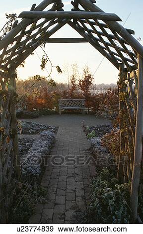 Stock Photo - Wooden arch and pergola in country garden in winter. Fotosearch