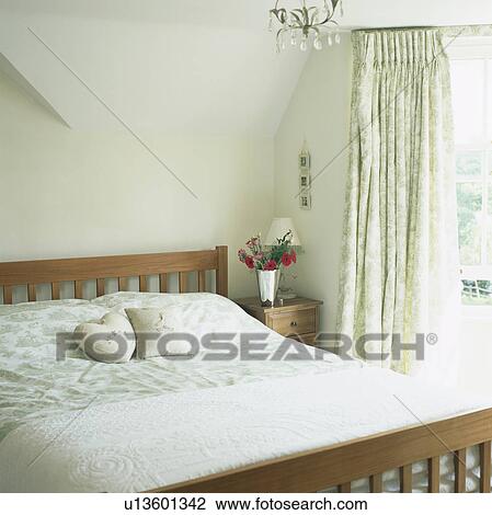Wooden bed in bedroom with green and white patterned curtains and bedlinen View Large Photo Image Stock Image - Wooden bed in bedroom with green and white patterned curtains and bedlinen. Fotosearch