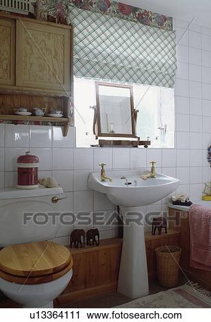 Wooden cabinet above toilet with wooden seat in small bathroom with green checked blind above pedestal basin View Large Photo Image Stock Image - Wooden cabinet above toilet with wooden seat in small bathroom with green checked blind above pedestal basin. Fotosearch