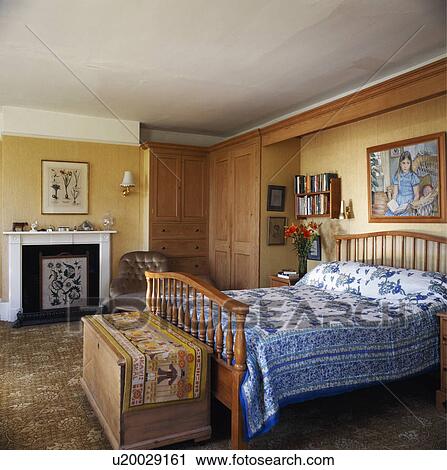Wooden chest below pine bed with blue+white bedcover in neutral bedroom with fireplace and patterned carpet View Large Photo Image Stock Image - Wooden chest below pine bed with blue+white bedcover in neutral bedroom with fireplace and patterned carpet. Fotosearch