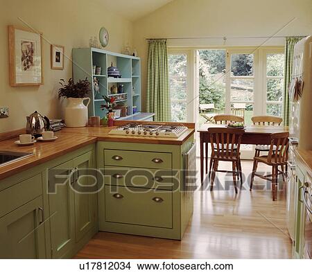 Wooden flooring in cream kitchen dining room with pastel green fitted cupboards and hob set into wooden worktop View Large Photo Image Picture - Wooden flooring in cream kitchen dining room with pastel green fitted cupboards and hob set into wooden worktop. Fotosearch