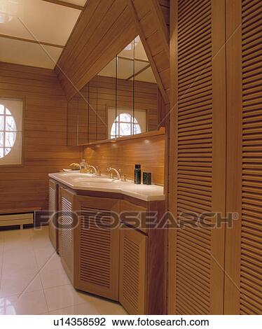 Wooden louvre doors on fitted cupboard in modern panelled bathroom with mirrored cabinets above basins View Large Photo Image Stock Image - Wooden louvre doors on fitted cupboard in modern panelled bathroom with mirrored cabinets above basins. Fotosearch