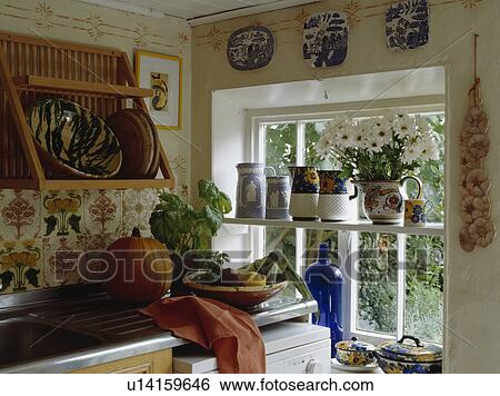 Wooden plate rack above sink in cottage kitchen with jugs on shelf across window View Large Photo Image Stock Photograph - Wooden plate rack above sink in cottage kitchen with jugs on shelf across window. Fotosearch