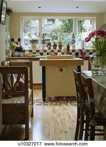 Stock Photo - Wooden settle in small kitchen with island unit and wooden flooring. Fotosearch