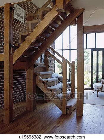 Wooden staircase in hall with wooden flooring in barn conversion with white rug View Large Photo Image Stock Image - Wooden staircase in hall with wooden flooring in barn conversion with white rug. Fotosearch