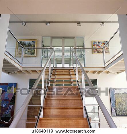 Wooden staircase with metal handrail and bannisters in modern white hall View Large Photo Image Stock Photo - Wooden staircase with metal handrail and bannisters in modern white hall . Fotosearch