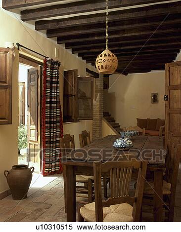 Wooden table and chairs in traditional Spanish country diningroom with beamed ceiling View Large Photo Image Stock Photography - Wooden table and chairs in traditional Spanish country diningroom with beamed ceiling. Fotosearch