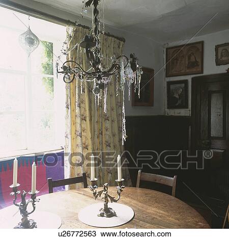 Wrought iron chandelier above wooden table in cottage dining room View Large Photo Image Stock Image - Wrought iron chandelier above wooden table in cottage dining room. Fotosearch