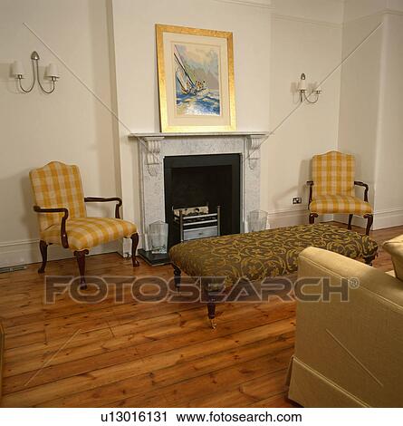 Yellow checked armchairs and upholstered stool in front of fireplace in living room with wooden floor View Large Photo Image Stock Image - Yellow checked armchairs and upholstered stool in front of fireplace in living room with wooden floor. Fotosearch
