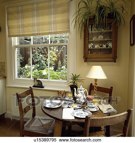 Yellow checked blind at window in small yellow dining room with small circular table set for breakfast View Large Photo Image Stock Photography - Yellow checked blind at window in small yellow dining room with small circular table set for breakfast. Fotosearch