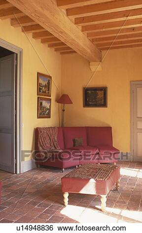 Stock Photograph - Yellow livingroom with beamed ceiling and terracotta tiled floor. Fotosearch