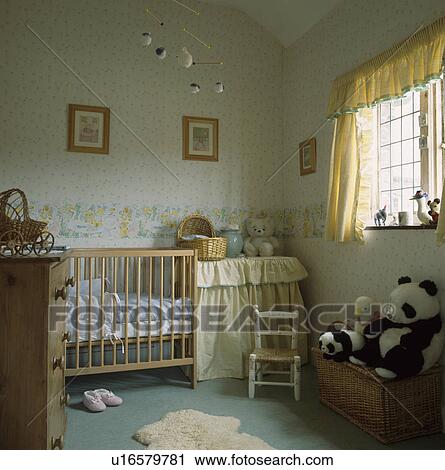 パステル 黄色いカーテン そして 壁紙をパターン装飾した 中に 赤ん坊 託児所 で 木製である 折畳み式ベッド そして 小さい 白 椅子 ストックイメージ U Fotosearch