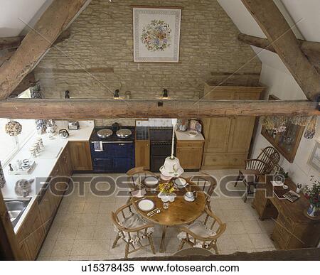Aerial view of circular wooden dining table and chairs in barn conversion kitchen with stone walls and Aga oven View Large Photo Image Stock Photography - Aerial view of circular wooden dining table and chairs in barn conversion kitchen with stone walls and Aga oven. Fotosearch