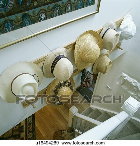 Stock Photo - Aerial view of straw hats on pegboard above white staircase. Fotosearch
