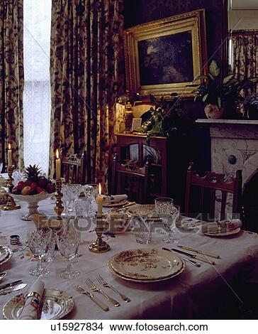 Antique china and silver cutlery on white tablecloth in traditional dining room with large gilt-framed picture View Large Photo Image Picture - Antique china and silver cutlery on white tablecloth in traditional dining room with large gilt-framed picture. Fotosearch