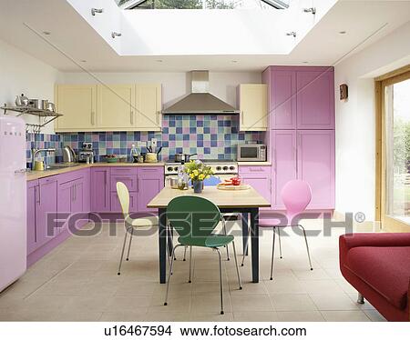 Arne Jacobsen pastel Ant chairs and wood table in modern kitchen extension with pink cupboards and cream floor tiles View Large Photo Image Picture - Arne Jacobsen pastel Ant chairs and wood table in modern kitchen extension with pink cupboards and cream floor tiles. Fotosearch