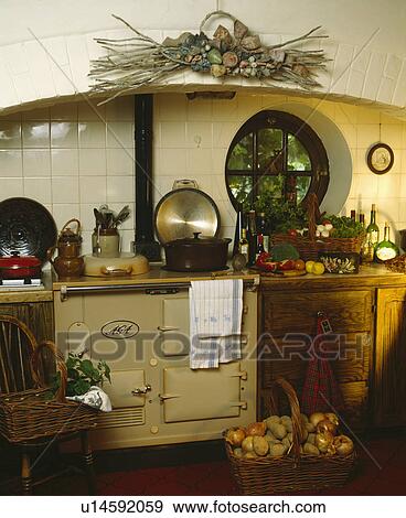 Basket of onions and potatoes in front of cream Aga in cottage kitchen with circular window View Large Photo Image Stock Photo - Basket of onions and potatoes in front of cream Aga in cottage kitchen with circular window. Fotosearch