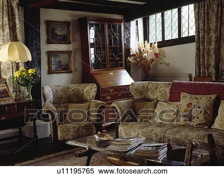 Stock Photography - Beamed country living room with beige patterned sofa and matching armchair. Fotosearch