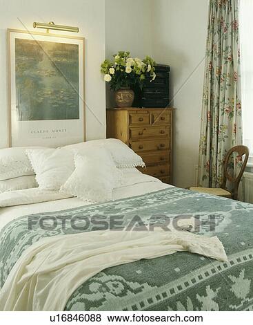 Bedroom with picture and lighting above bed with white pillows and linen and patterned green throw on the bed View Large Photo Image Stock Photo - Bedroom with picture and lighting above bed with white pillows and linen and patterned green throw on the bed. Fotosearch