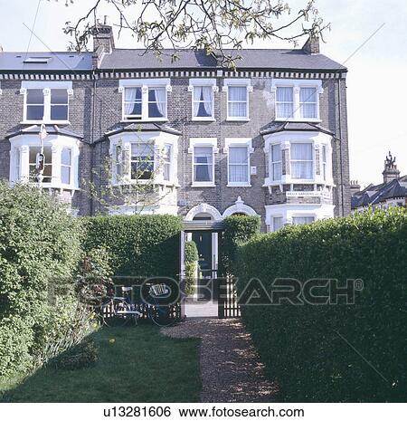 Bicycle in small town garden bordered by tall hedges in front of large terraced Victorian townhouses View Large Photo Image Stock Photograph - Bicycle in small town garden bordered by tall hedges in front of large terraced Victorian townhouses. Fotosearch