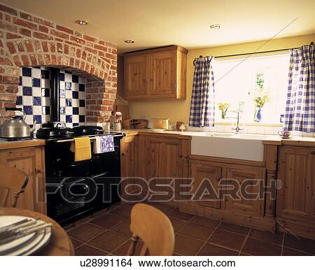 Black Aga In Brick Fireplace With Blue White Tiles In Cottage