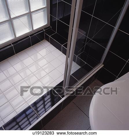 Stock Image - Black and white shower with glass screen doors.. Fotosearch