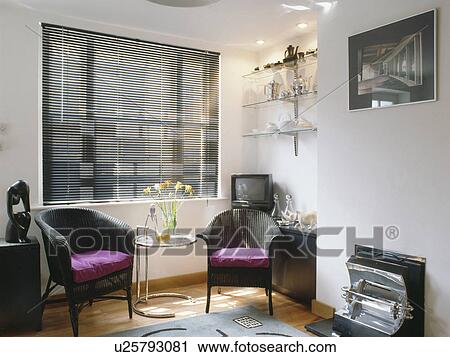Black "Lloyd Loom" chairs on either side of "Eileen Gray" table in modern living room with old electric fire & black blind View Large Photo Image Stock Image - Black "Lloyd Loom" chairs on either side of "Eileen Gray" table in modern living room with old electric fire & black blind. Fotosearch