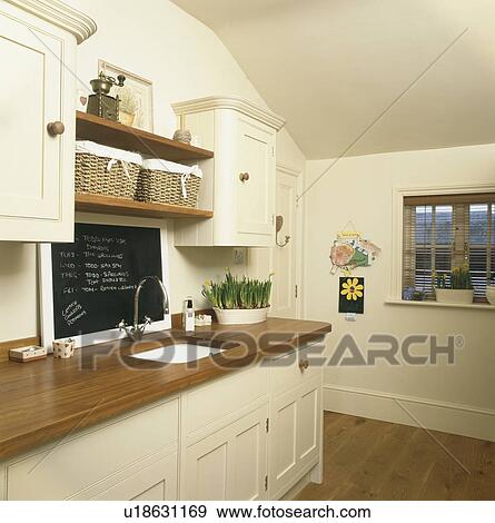 Blackboard above sink in wooden worktop in cream kitchen View Large Photo Image Stock Photo - Blackboard above sink in wooden worktop in cream kitchen. Fotosearch