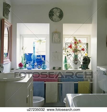 Blue glassware on windowsill of small family bathroom with pastel towels on storage rail View Large Photo Image Stock Image - Blue glassware on windowsill of small family bathroom with pastel towels on storage rail. Fotosearch