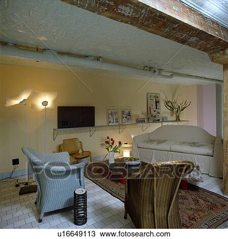 Stock Image - Blue Lloyd Loom armchairs in modern loft conversion living room. Fotosearch