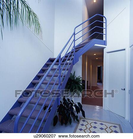 Stock Photo - Blue metal staircase in modern white hall with houseplants. Fotosearch