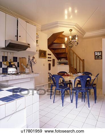 Blue plastic chairs and white Aaro Saarinen table in modern white kitchen with white tiled floor View Large Photo Image Stock Photo - Blue plastic chairs and white Aaro Saarinen table in modern white kitchen with white tiled floor. Fotosearch