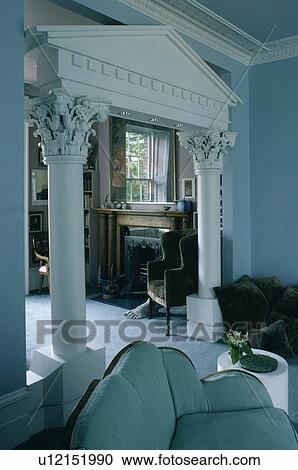 Stock Image - Blue sofa in living room with neo-classical arch. Fotosearch