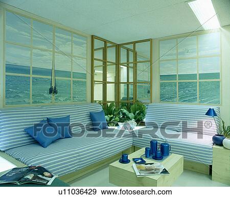 Stock Photo - Blue striped sofas in iving room with seascape murals on walls. Fotosearch