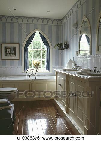 Blue Striped Wallpaper And Polished Wooden Flooring In Bathroom With Gothic Windows Stock Photograph