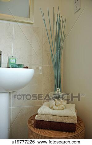 Blue twigs behind small table with pile of neutral towels and soaps in a glass vase in modern tiled bathroom View Large Photo Image Stock Photograph - Blue twigs behind small table with pile of neutral towels and soaps in a glass vase in modern tiled bathroom. Fotosearch
